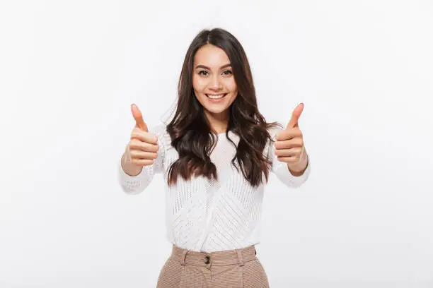 Portrait of a smiling asian businesswoman showing thumbs up isolated over white background