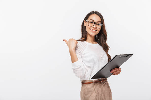 Portrait of a smiling asian businesswoman Portrait of a smiling asian businesswoman holding blank clipboard and pointing finger away isolated over white background one business woman stock pictures, royalty-free photos & images