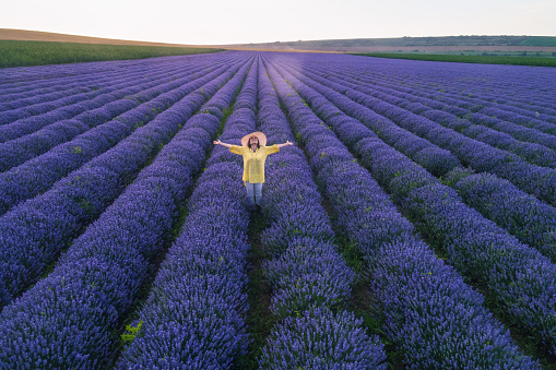 Eco tourism in the lavender. Getting away from it all, while exploring nature. Young woman enjoying the wind blowing through her hair in the blooming lavender fields, while on vacation.