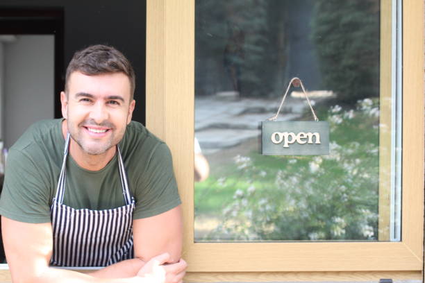 istock Worker smiling with open signboard in the background 1303512340