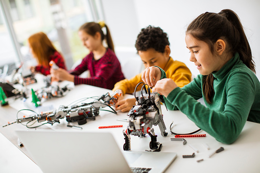 Niños felices programando juguetes eléctricos y robots en el aula de robótica photo