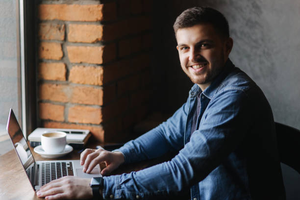 istock Man with a beard uses a laptop in a cafe 1303514229