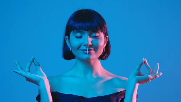istock Young woman meditate and open eyes isolated on blue neon copyspace 1303517253