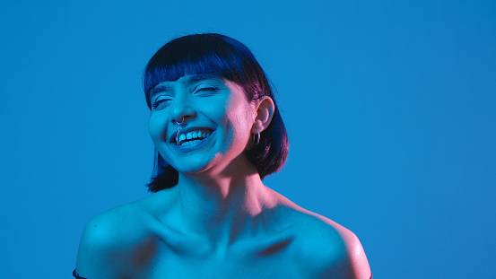 Young mixed race brunette cheerful woman laugh isolated on blue neon copyspace