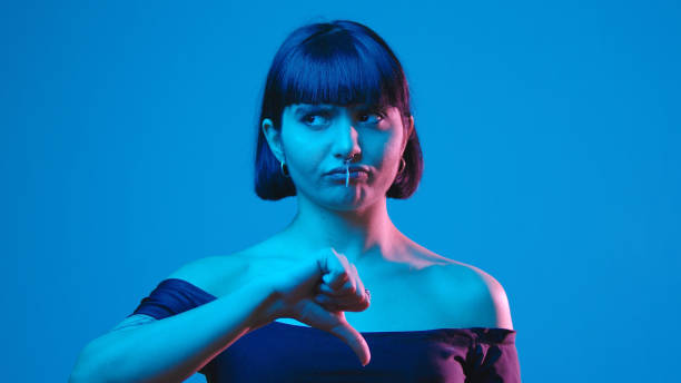 istock Young woman thumb down gesture isolated on blue neon copyspace 1303517464