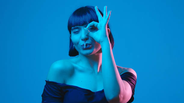 istock Young woman ok gesture isolated on blue neon copyspace 1303517483