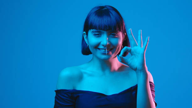 istock Young woman ok gesture isolated on blue neon copyspace 1303517495