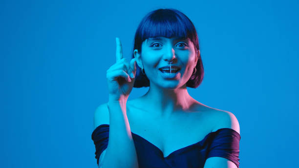 istock Young woman smile think aha idea eureka isolated on blue neon copyspace 1303517526