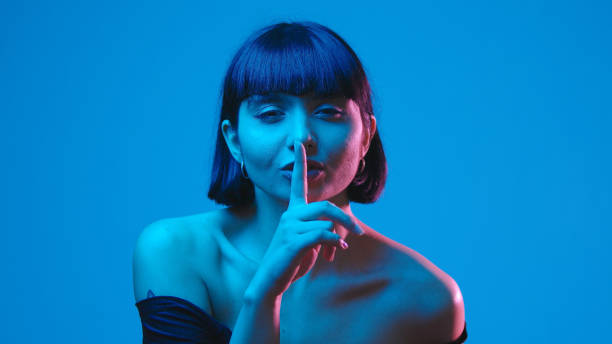 Young mixed race brunette woman shhh gesture finger isolated on blue neon copyspace