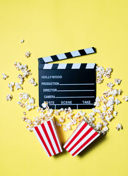 istock Movie clapperboard and popcorn on yellow background 1303517644