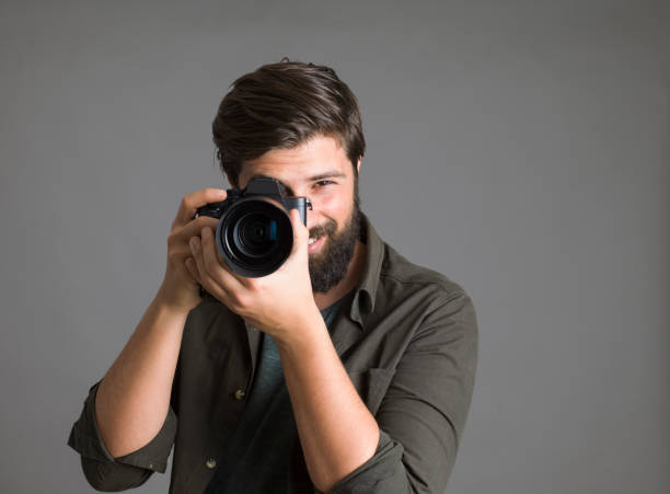 istock Portrait of a photographer using a digital SLR camera over gray background 1303518574