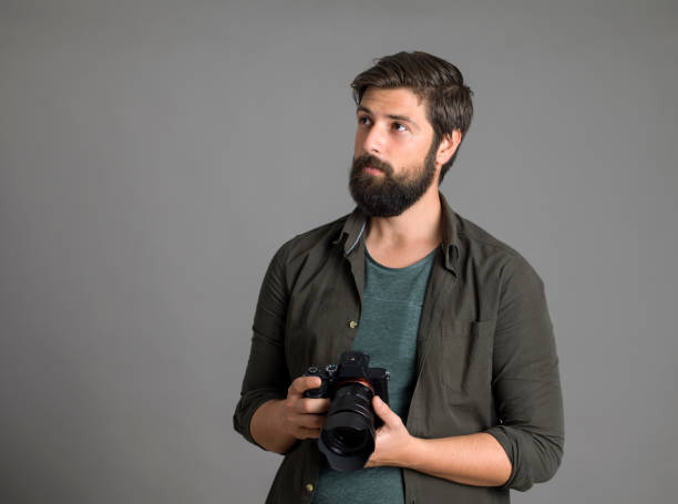 istock Portrait of a photographer using a digital SLR camera over gray background 1303518607