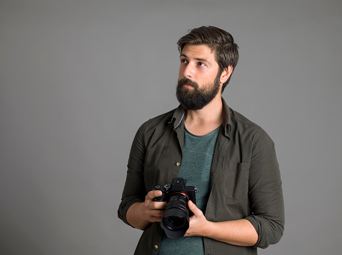 Portrait of a photographer using a digital SLR camera over gray background