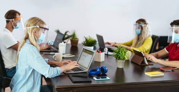 istock Young people in co-working creative space wearing surgical mask protection for preventing corona virus spread - Millennial friends working with ppe equipment - Social distancing and technology concept 1303519079