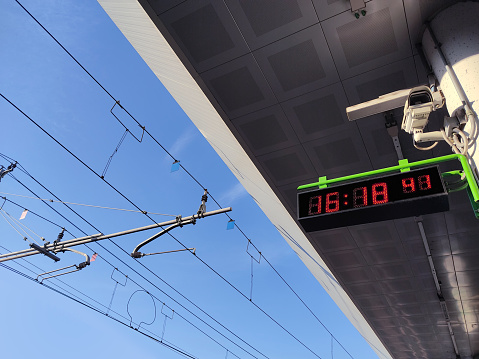 a clock hanging high on a pole with blue sky in the background