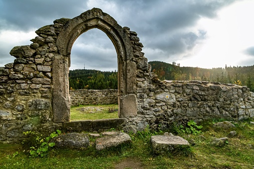 Tridomi, Czech Republic - October 29 2016: Ruins of the church of St Nicholas, svaty Mikulas, standing in the middle of the forest. View of the door. Sun over horizon.