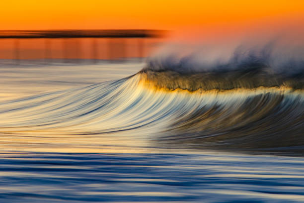 istock Smooth wave breaking on the beach on golden sunrise 1303522843