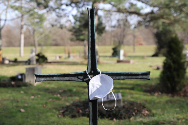istock cross on a grave with mouth-nose-protection 1303522925