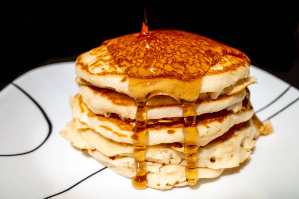 istock Syrup pouring onto a stack of fluffy pancakes. 1303523731