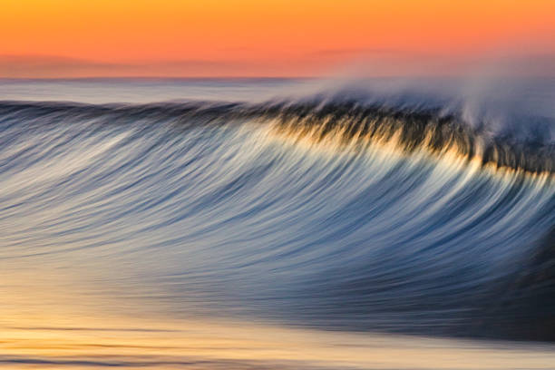 istock Golden peak wave breaking on the beach with warm sunrise 1303523762
