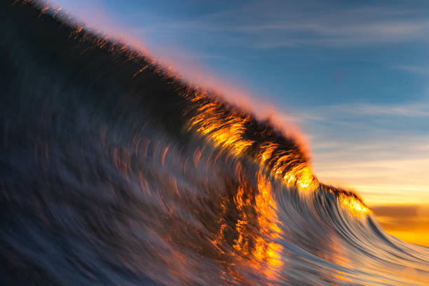 Close up of smooth wave breaking on the beach with warm sunrise