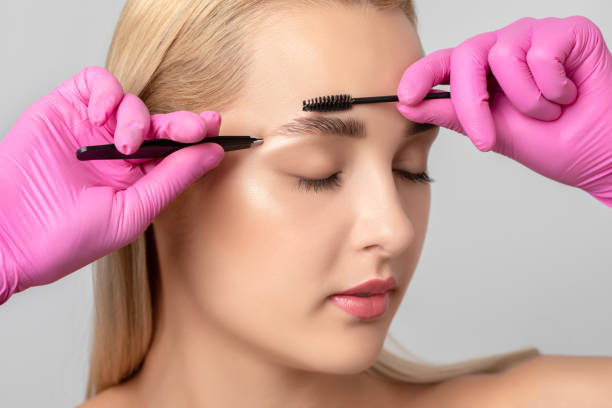 istock Makeup artist combs and plucks eyebrows after dyeing in a beauty salon.Professional makeup and cosmetology skin care. 1303528904