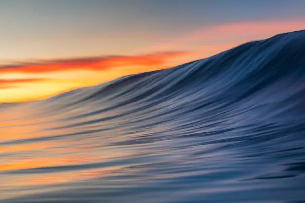 Photo of Close up of smooth wave forming on the beach with warm sunrise