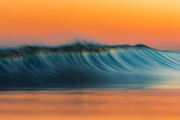 istock Golden peak wave breaking on the beach with warm sunrise 1303530044
