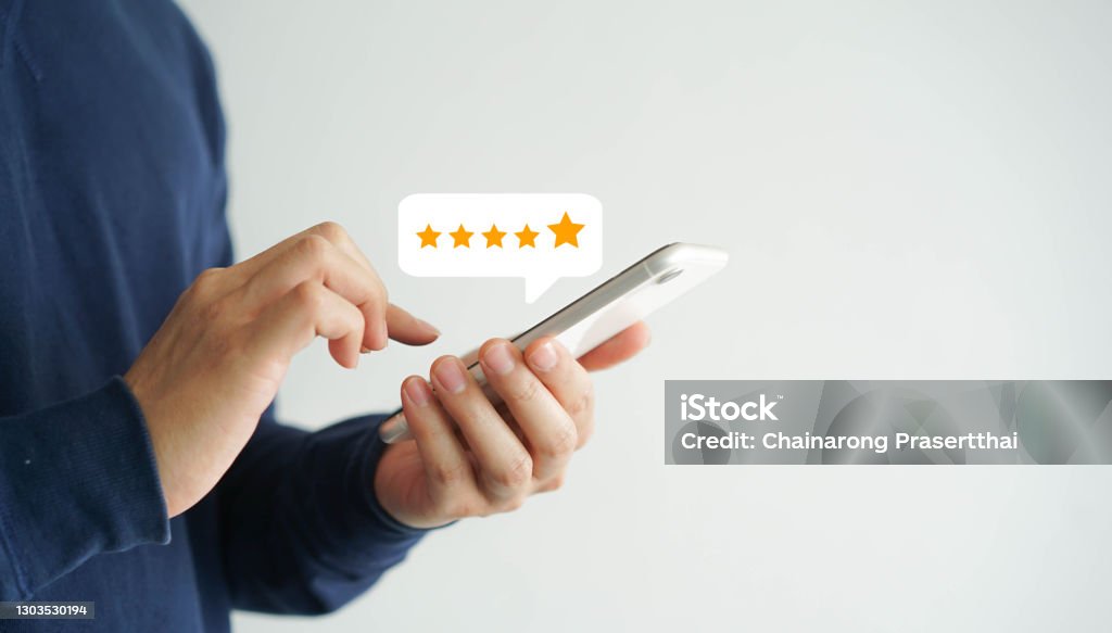 close up on customer man hand pressing on smartphone screen with  five star rating feedback icon and press level good rank for giving best score point to review the service , technology business concept Rating Stock Photo