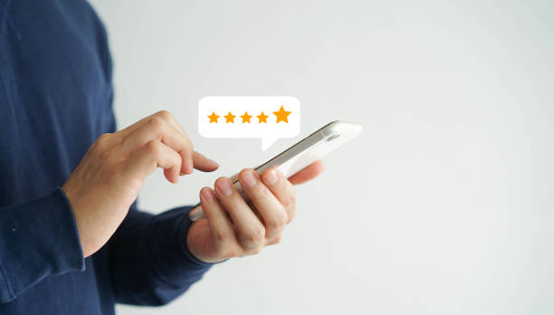 close up on customer man hand pressing on smartphone screen with  five star rating feedback icon and press level good rank for giving best score point to review the service , technology business concept stock photo