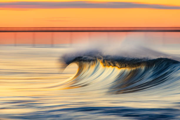 istock Golden peak wave breaking on the beach with warm sunrise 1303530232