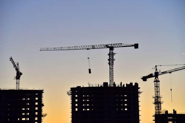 istock Tower cranes in action at construction site on sunset background. 1303530286