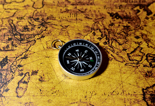 Compass on map. Tourist compass for orientation on the terrain. Magnetic declination calculator. Historical explorer help. Map reading and land navigation concept. Orient on maps