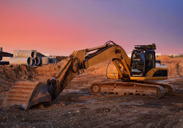 istock Excavator on earthworks at construction site on sunset backround. Excavators on foundation work 1303531304