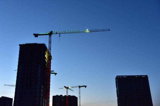 istock Tower cranes in action at construction site on sunset background. 1303531355