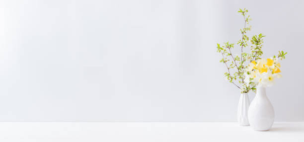 istock Home interior with easter decor. Daffodils in a vase, spring flowers on a light background 1303531427