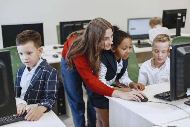 istock Computer science teacher shows the children how to use a computer. 1303532476