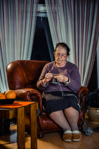 istock Senior Woman sitting on a sofa and knitting 1303532550