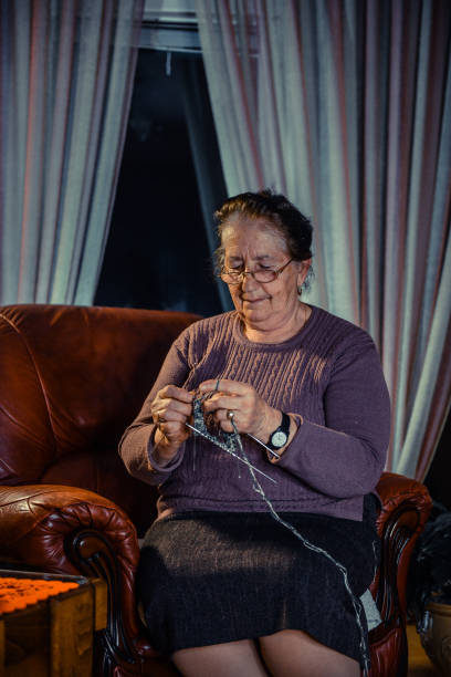 istock Senior Woman sitting on a sofa and knitting 1303532569