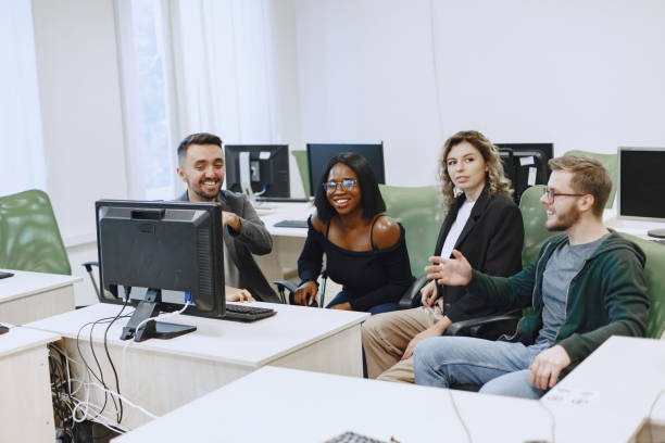 istock People sitting at a table in a computer room. 1303532627