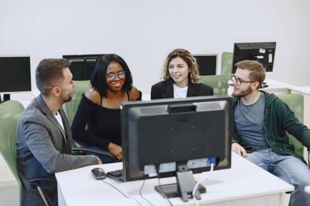 istock People sitting at a table in a computer room. 1303532669