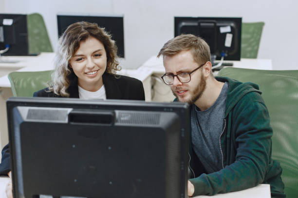 istock People sitting at a table in a computer room. 1303532754