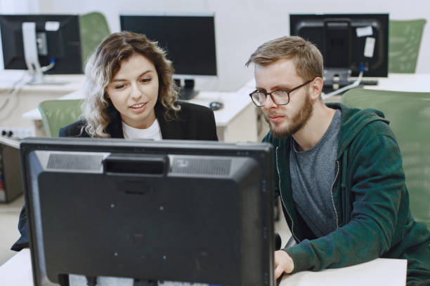 istock People sitting at a table in a computer room. 1303532761