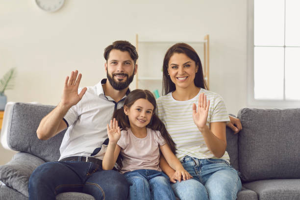 istock Happy family looking at laptop web camera while sitting on the couch at home. 1303539715