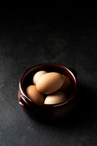 Brown eggs in ceramic bowl on grey background. Easter eggs. Shot from directly above.