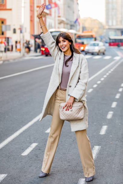 una mujer adulta que engancha un taxi en el distrito financiero, sonriendo. - freedom on the phone urgency telephone fotografías e imágenes de stock