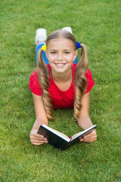 School time. Interesting stories for kids. Study with pleasure. Time for great stories. Little child reading book outdoors. Schoolgirl read stories while relaxing green lawn. Cute pupil enjoy reading. hora de la escuela. historias interesantes para niños. estudia con placer. es hora de grandes historias. libro de lectura para niños pequeños al aire libre. colegiala leyó historias mientras relajaba el césped verde. lindo alumno disfrutar de la lectu