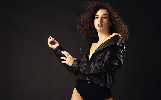 Portrait of fashion model in leather jacket front of black background.