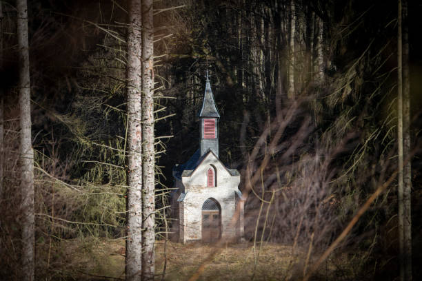 istock chapel hidden between trees in the woods 1303553631
