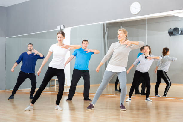 Adult people training in dance studio Smiling females and males doing Zumba dance workout during group classes in fitness center zumba image stock pictures, royalty-free photos & images